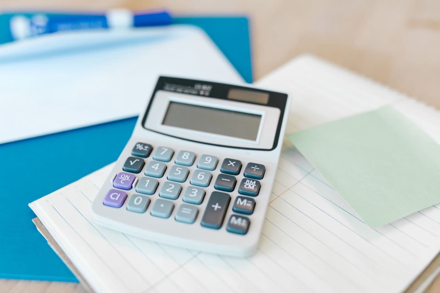Calculatrice posée sur un carnet, calcul de coûts